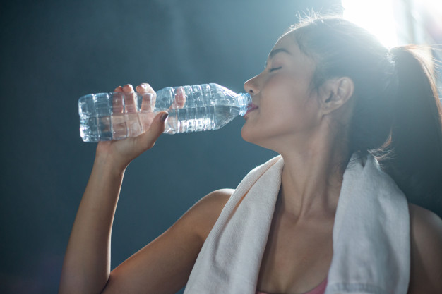 Women after exercise drink water from bottles and handkerchiefs in the gym. Free Photo